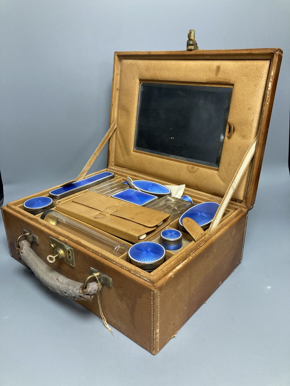 A late 19th/early 20th century French ten piece white metal and blue guilloche enamel travelling toilet set in leather case,